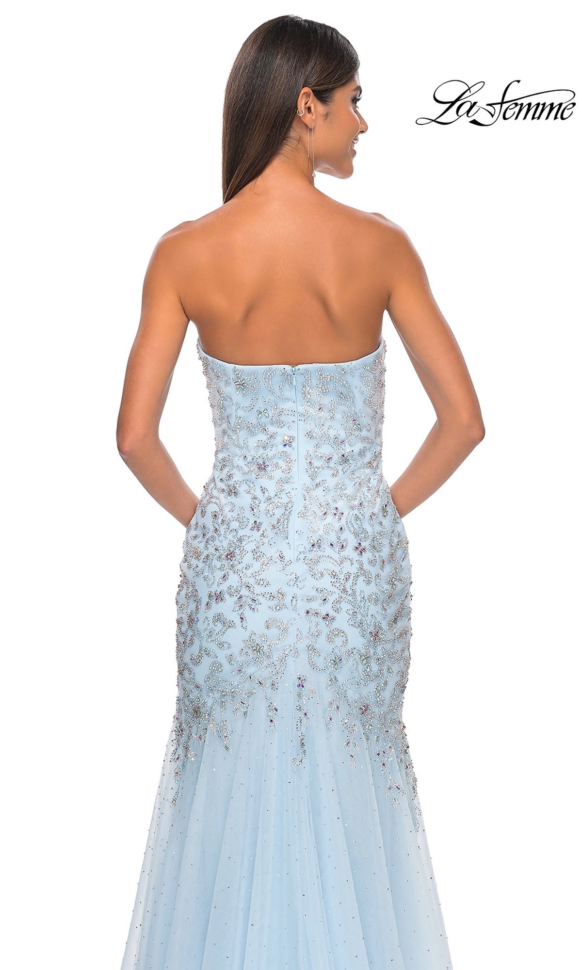 A woman models the La Femme Strapless Long Beaded Prom Dress 32197 in light blue, its intricate beadwork shimmering. She’s photographed from the back against a white background, with the La Femme logo in the upper right corner.